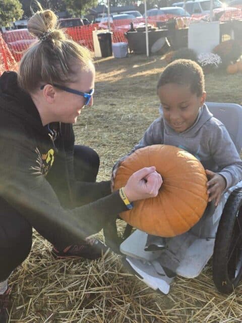 Melissa Seward and Ethan Rice with Platypus Adventures holding a large pumpkin at the Golden Strip Pumpkin Patch